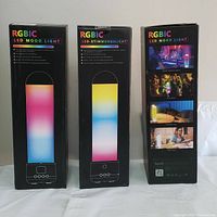 Front of three RGBIC LED Mood Light boxes showing tubular colorful LED lights and basic product branding.