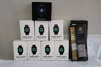Seven boxed generic black smart watches labeled 'Smart Watch Your Sports Partner' stacked with one black boxed TicWatch GTH Pro on top.