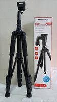 Full view of the Merkury Innovations 360 Trigger tripod next to its original retail box showing branding and product image