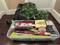 Overview of all lot contents showing tree sections in bag, stand and container of wrapping accessories