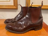 Side view of brown leather Chelsea boots, showing smooth leather upper with some creasing and elastic side panel.