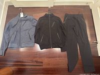 Lot of men's Lululemon clothing laid flat on floor showing two jackets and one pair of pants, all size Medium.
