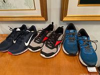 Front view of three pairs of men's running shoes side by side showing colors and condition