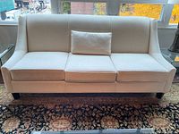 Front view of the tan fabric sofa without pillows showing cushion and arm details.