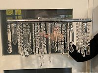 Front view of modern wall sconce light fixture with chrome finish and hanging crystal prisms.