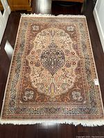 Full view of the Persian carpet laid out on hardwood floor showing central medallion, border pattern and fringed edges