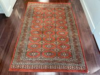 Full view of rug laid flat on dark hardwood floor, showing overall pattern and condition