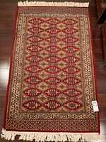 Full view of carpet laid flat on wood floor showing overall pattern, color and fringe