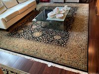 Wide view of rug under sofa and coffee table showing overall pattern, border, fringe
