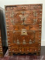 Front view of antique Korean chest showing wood grain and detailed brass hardware including butterfly motifs and handles.