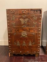 Frontal view of Korean Tansu chest showing wood grain, brass hardware, and detailed butterfly-shaped brass lock plate on double doors.