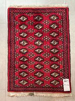 Full view of rectangular red Persian-style rug with repeating tan and ivory medallions and fringed ends