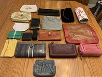 Overview of all 18 bags and wallets shown arranged on a wooden surface, showing size, color, and material variety.