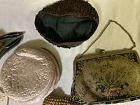 Photo showing four vintage evening bags: pink satin round bag, metal mesh gold-tone clutch, floral tapestry framed bag, brown beaded/sequined bag