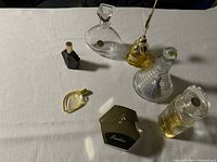 Top-down photo of seven perfume bottles arranged on a white surface showing shapes and contents.