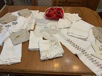 Overview of vintage linens collection including lace doilies, embroidered linens, and folded pieces on wooden table