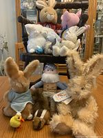 Wooden chair with stuffed animals including rabbits, a pig, a duck and a plush man figure arranged on and around the chair.