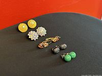 Image showing five pairs of vintage pierced earrings laid out on black surface with red background