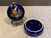 Closed and open views of cobalt blue porcelain trinket dish with gold decoration and classical couple scene on lid.