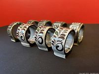 Eight hand-painted Tonala pottery napkin rings angled on a red background