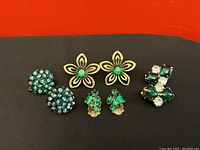 Front view of four pairs of vintage earrings arranged horizontally on a black surface.