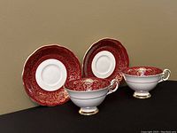 Side view of the two EB Foley china teacups and saucers showing the burgundy red and gold pattern.
