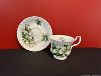 Teacup and saucer front view showing floral design and shape.