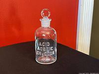 Front view of vintage clear glass apothecary jar with chemical label ACID ACETIC CH3COOH on red background