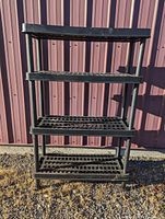 Full view of the black 4-tier plastic shelving unit showing its structure and shelf design.