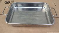 Top-down image of a rectangular stainless steel buffet server pan showing handles on each side and surface wear marks.