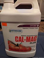Photo of the front label of a white plastic jug of Botanicare Cal-Mag Plus plant nutrient supplement, showing branding, nutrient info, and a tomato image.