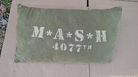 Green rectangular pillow with white 'M*A*S*H 4077th' text.
