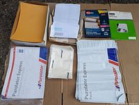 Box containing a variety of Purolator Express mailing bags, white security envelopes with windows, manilla envelopes, and Avery shipping labels and slips.