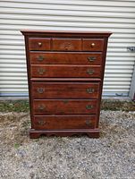 Front view of the wooden high boy dresser showing the drawer layout and hardware.