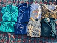 Lot of 8 ladies clothing items including sweaters, matching sets, embroidered sweatshirt, button-up shirts, and cardigans in various colors.