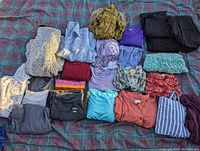 Overview of various ladies clothing items displayed laid out on a plaid surface showing sweaters, tops, leggings, and cardigans in different colors and patterns