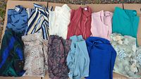 Photo showing 11 pieces of ladies dresswear including tops and skirts in various colors and patterns laid flat.