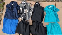 Photo showing four ladies dresswear sets with skirts and jackets/tops laid out on cardboard outdoors.