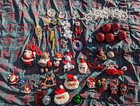 Full view of various Christmas tree ornaments including stars, apples, snowmen, and Santas laid on a plaid fabric.