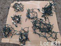 Photo of seven sets of tangled modern LED Christmas lights with green wiring and multi-colored bulbs laid out on cardboard