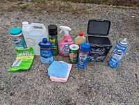 Full lot view showing all cleaning supplies arranged outdoors on gravel, including wipes, sprays, powders, and detergent bottles.