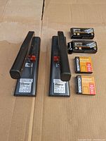 Photo showing two black Bostitch heavy duty staplers side by side with red levers and multiple boxes of Bostitch staples placed beside them.