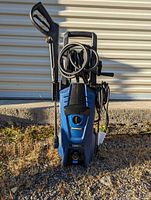 Front view of blue Simoniz electric pressure washer with power cable wrapped and spray gun attached.
