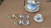 Overall lot shown outside on cardboard including ceramic wash set in blue and white and glass tealight holders
