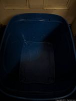 Top-down view showing the inside of the blue plastic storage bin, no lid present, some visible scratches inside.