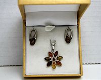 Set of amber floral pendant and drop earrings inside a gift box, showing front view of the pieces arranged neatly.