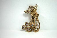 Front-facing image of an angel brooch playing a harp, decorated with aurora borealis rhinestones on robe, wings, and halo.