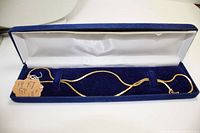 Gold filled chain necklace displayed in a blue velvet box with white satin interior lining, shown folded with a paper tag indicating '14kt GF 18"'