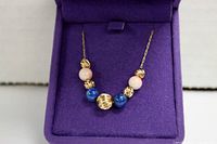 Close view of the 14K gold chain necklace with alternating gold, pink, and blue beads showing the bent gold ball bead detail.