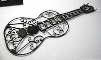 Image showing full length of the decorative handmade metal guitar, displaying the overall shape and intricate scrollwork.